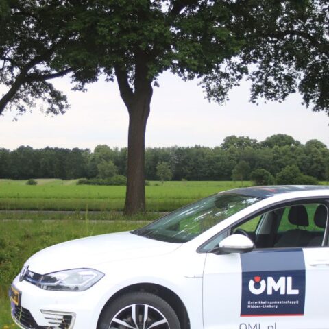 Witte bedrijfsauto van OML met groen op de achtergrond